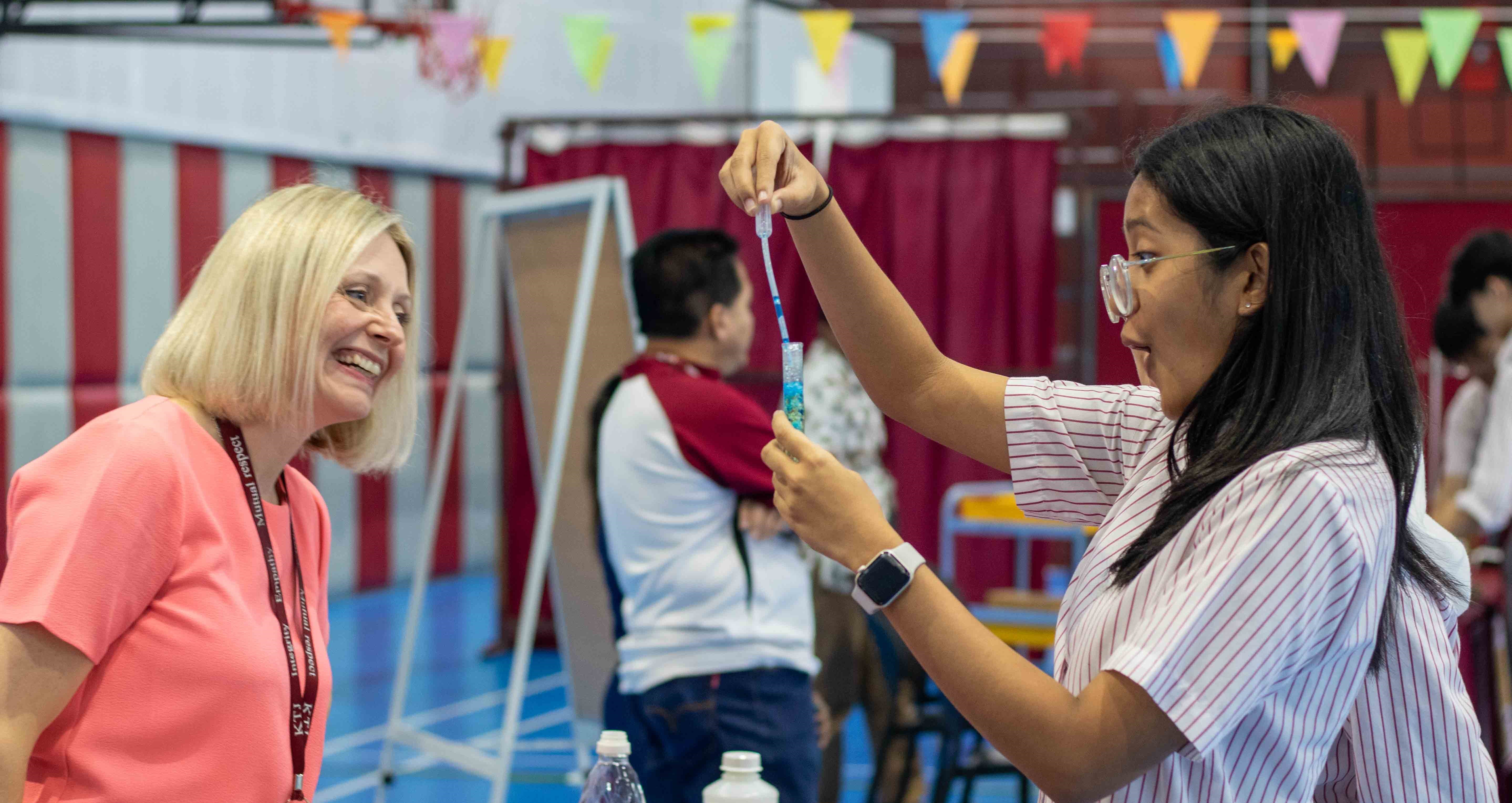 Project 3 focused on live feedback to cater for the different needs of students. Two students pouring a substance into a test tube whilst their teacher smiles.